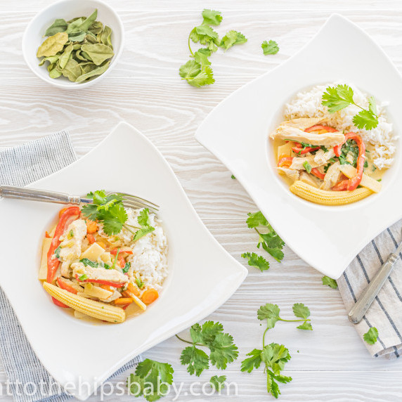 two bowls of Thai Green Curry over rice, with scattered cilantro leaves.