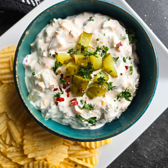 A blue rimmed bowl filled with chunky white dill pickle dip.