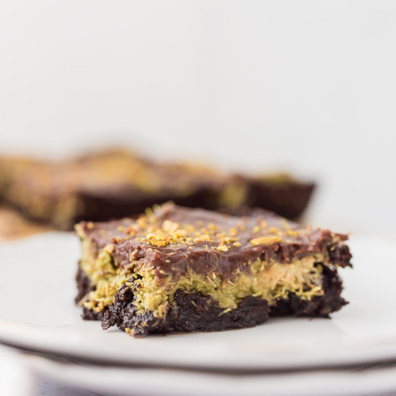 Dubai Chocolate Avocado Brownie on white plate with remaining brownies blurred in the background 