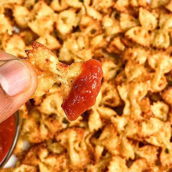 Top shot of pasta chips with two bowls of red and white dipping sauce.