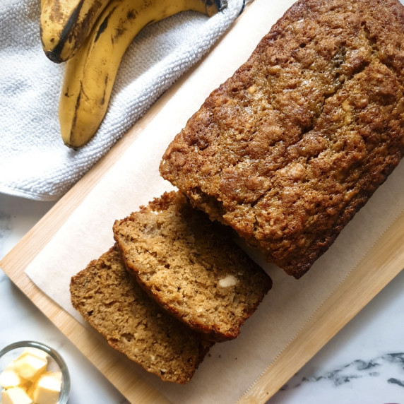 Two Bananas Banana bread recipe on a wooden cutting board with two slices cut.
