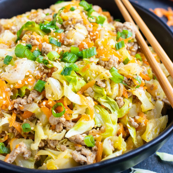 Egg Roll in a Bowl RECIPE inside of a black bowl with chopsticks over the bowl on the side.