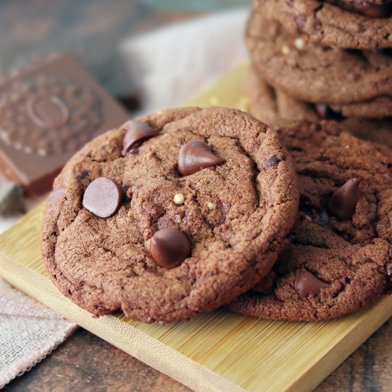 Ferrero Rocher Chocolate Chip Cookies stacked on a wooden board.