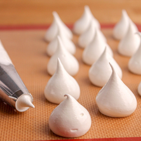 French Meringue pipped into cookies on baking sheet with piping bag