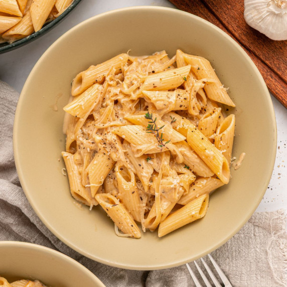 A bowl of pasta that is made with caramelized onions and cheese. 