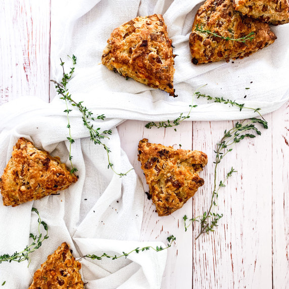 French onion scones on a white linen on white shiplap with strands of fresh thyme