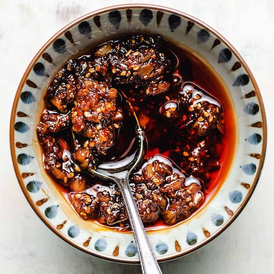 Garlic chili sauce in a white blue and brown bowl with a stainless steel spoon