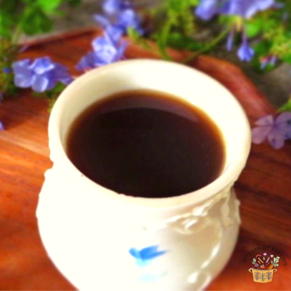 Ginger Tulsi Tea in a white cup on a brown board with purple flowers