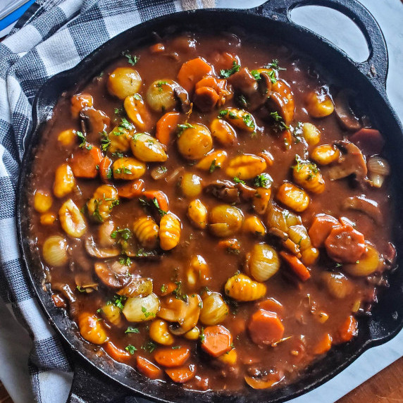 A skillet of rich, gnocchi bourguignon. Tender gnocchi, rich gravy, carrots, & pearl onions.