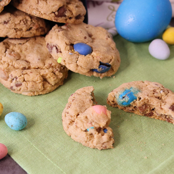 Hard boiled egg chocolate chip cookies spilling onto a napkin with colorful eggs, one broken open.