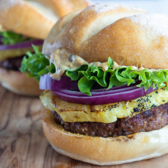 Burger bun with beef, pinapple, red onions, green lettuce and curry aioli.