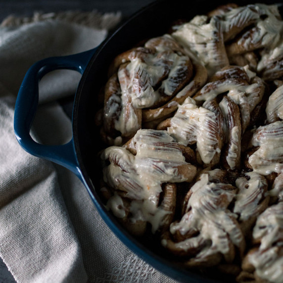 A pan of healthy braided cinnamon buns with a sour cream glaze 