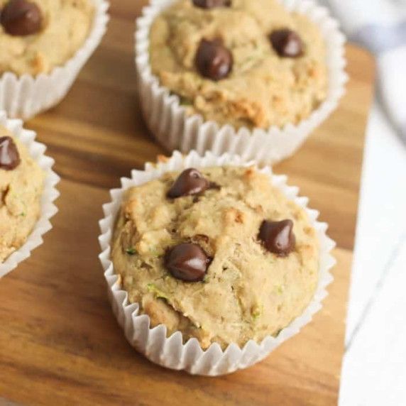 Several muffins with chocolate chips on a cutting board.