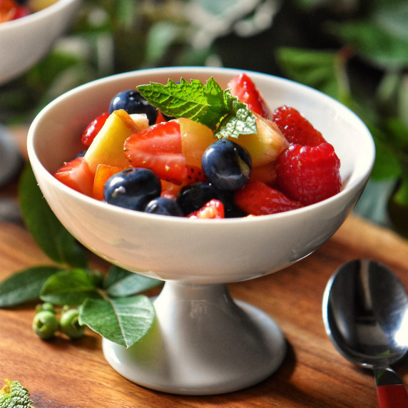 A fruit salad in a white dessert cup.