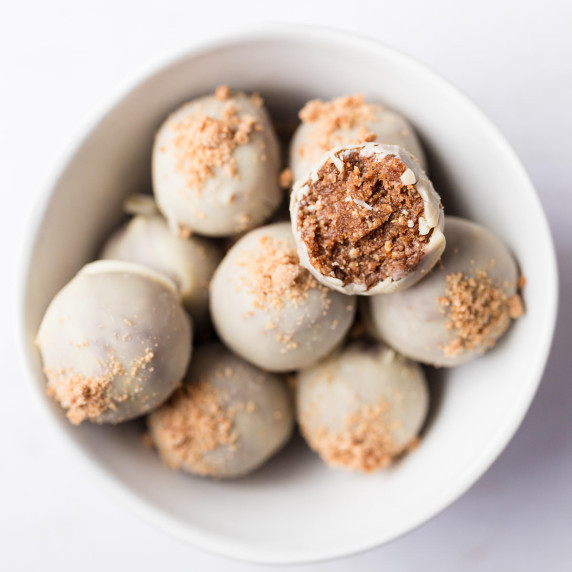 Healthy gingerbread energy bites coated in white chocolate in a white bowl on a white surface