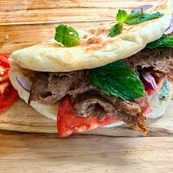 Juicy homemade doner kebab sandwich with seasoned ground beef, fresh veggies, and yogurt sauce.