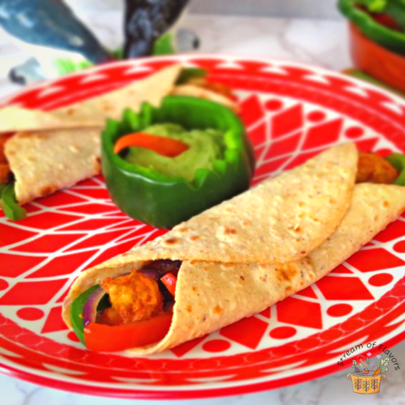 Shrip fajitas on a red plate served with guacamole and salsa