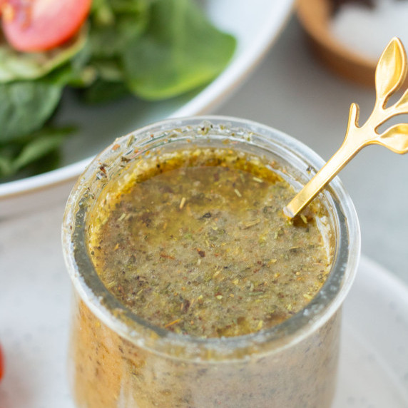 finished homemade italian dressing next to spinach salad