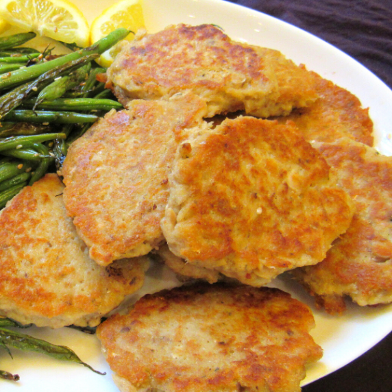Crispy moist salmon patties served on a white plate.