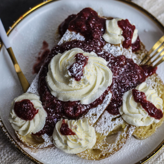 Slices of sourdough French toast topped with whipped cream and homemade strawberry compote.