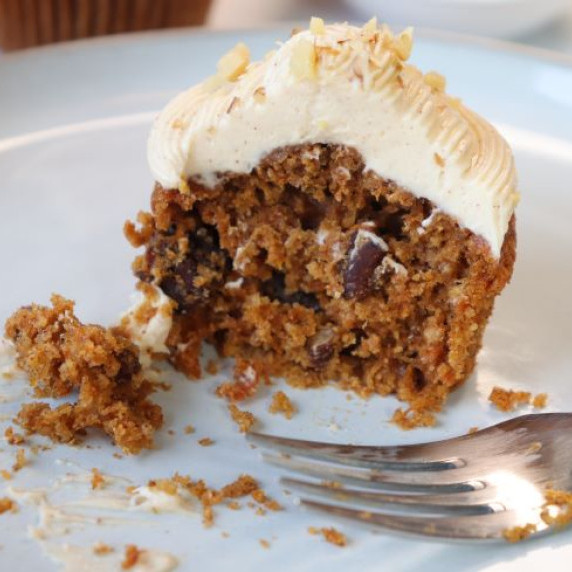 sweet potato carrot cake cupcake topped with a maple cream cheese frosting on a plate. 