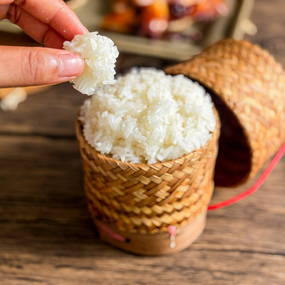 Thai sticky rice served in a bamboo basket on a wooden table.