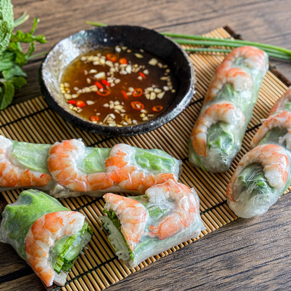 Close-up of Vietnamese fresh spring rolls served with dipping sauce on the side.