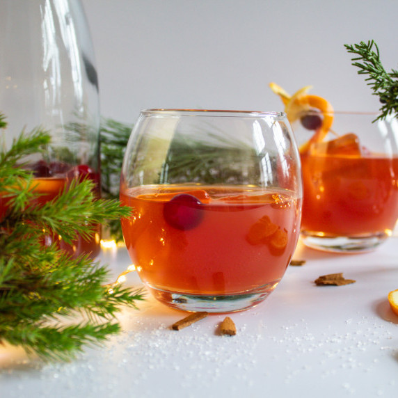 a glass of holiday punch with twinkling lights in the background.