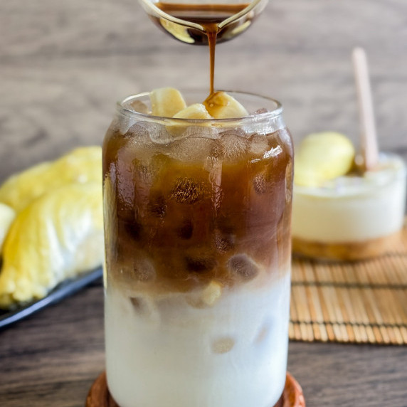 Iced durian coffee in a glass with creamy milk and dark coffee layers.
