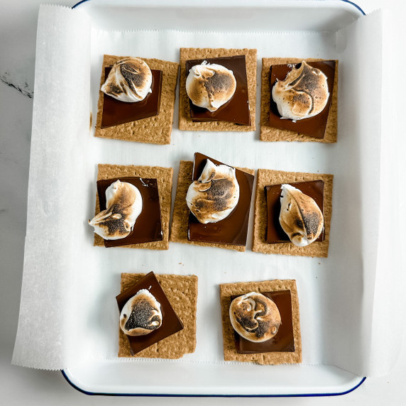 vanilla bean marshmallow fluff on chocolate and gram cracker placed on top of parchment sheet pan