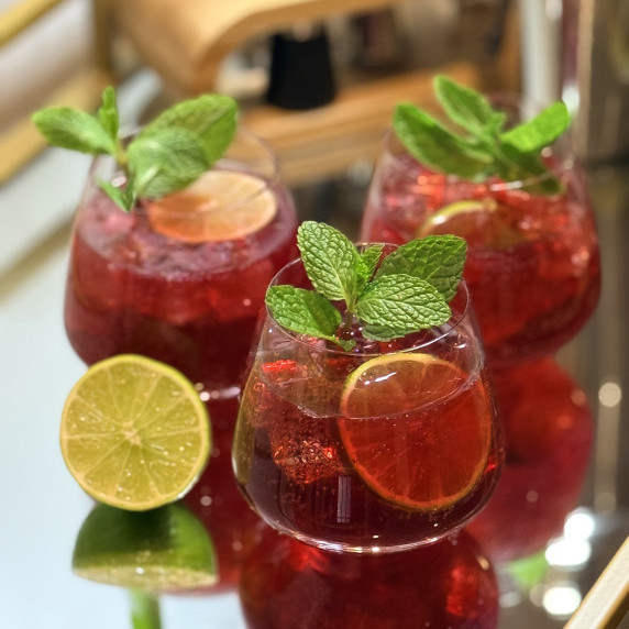 Three glasses of pomegranate lime mocktail are beautifully garnished with fresh mint and lime wheels