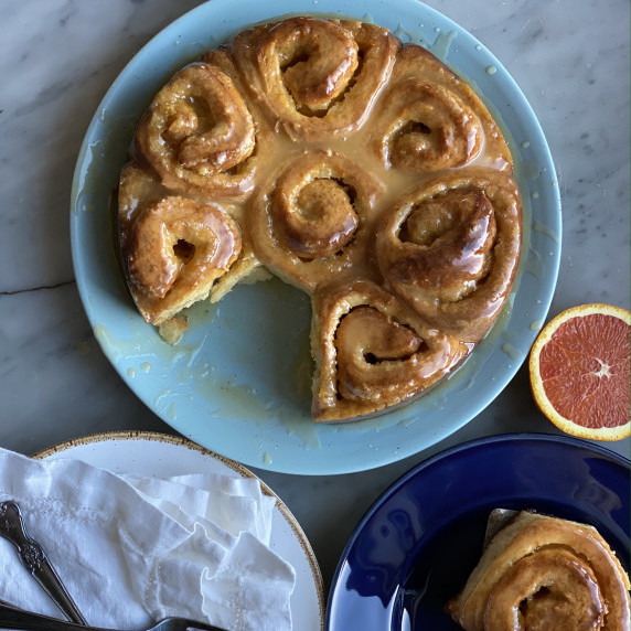 orange rolls on a plate with 1 removed on another plate with a cara cara orange and white napkins