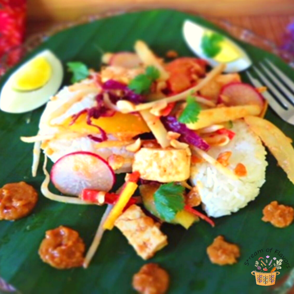 Indonesian gado gado salad with spicy peanut sauce, rice cakes, eggs and vegetables on a banana leaf