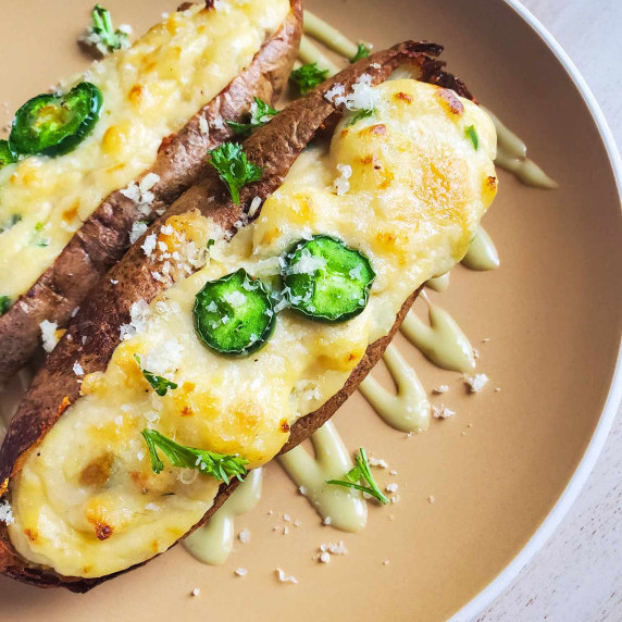 Golden mash stuffed inside crisp, brown tater skins on a beige plate.