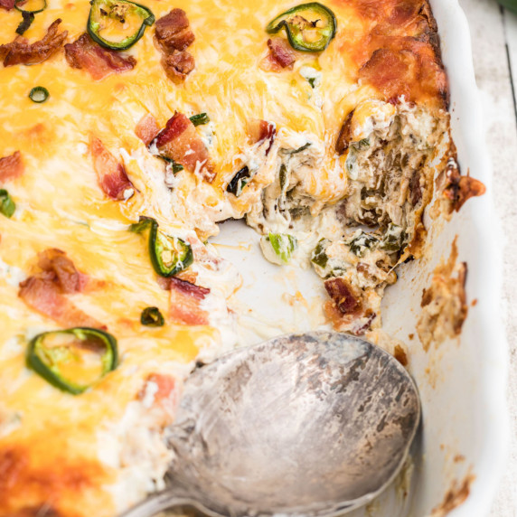 A jalapeno popper tater tot casserole with a spoon resting in the dish.