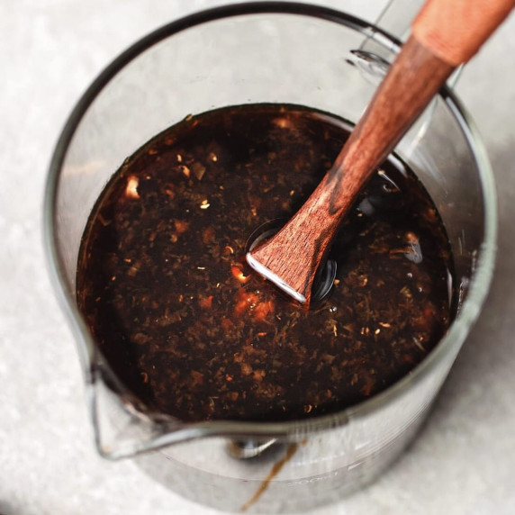 Teriyaki sauce in a measuring glass with a spoon on a countertop