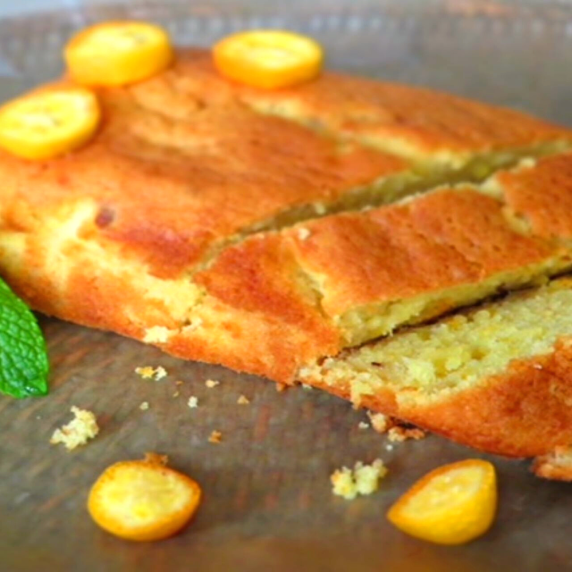 Kumquat loaf cake with sliced kumquats on a brown board