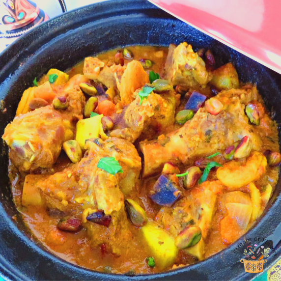 Lamb stew with apricots garnished with pistachios in a red tagine with a Moroccan teapot
