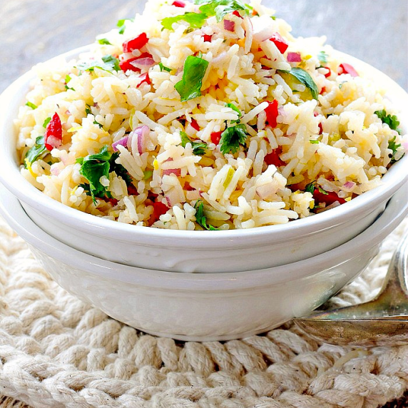 A white bowl with rice, red peppers, onions and spices and herbs