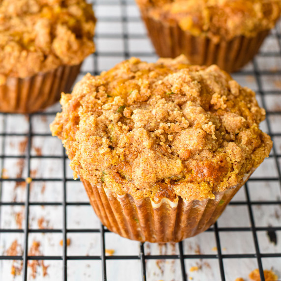 pumpkin zucchini muffins on a black wire cooling rack on a white background