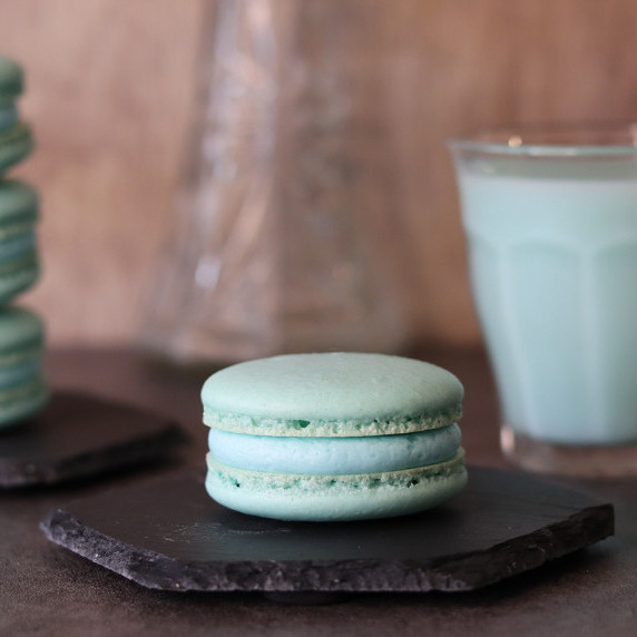 A Mandalorian Macaron on a black hexagon board with a glass of blue milk in the background