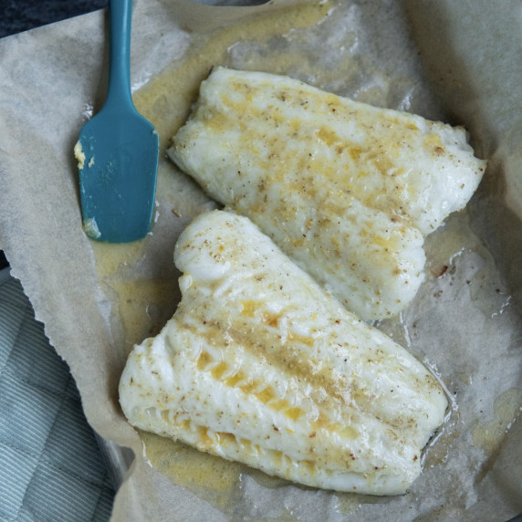 baking tray with parchment paper and two oven roasted white fish with melted miso butter. 