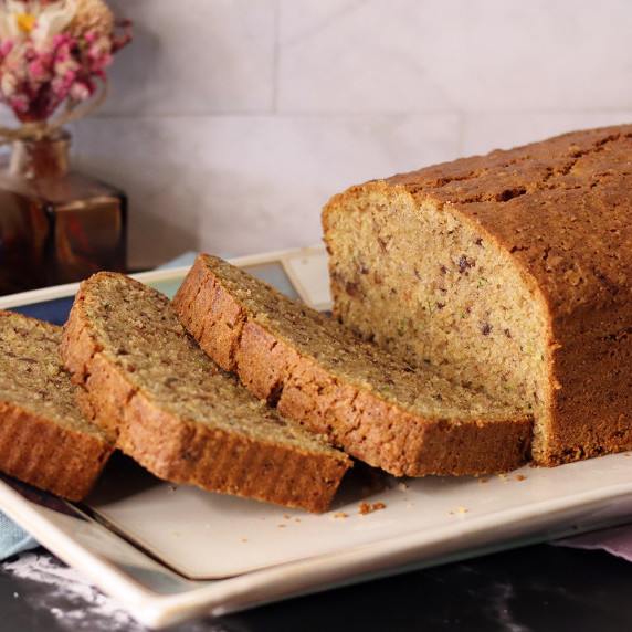 Zucchini bread sliced on a white platter with blue tile trim.