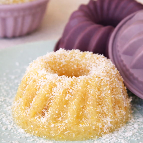 Orange Semolina Halva shaped in a small cake mold, sprinkled with shredded coconut.