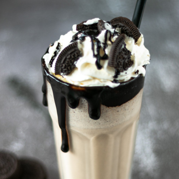 Macro shot oreo ice coffee with whipped cream and oreo on top, grey background
