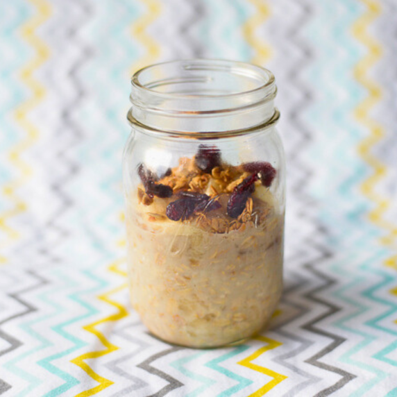 Glass ball jar filled 3/4 with overnight oats and fruit on top of oatmeal.