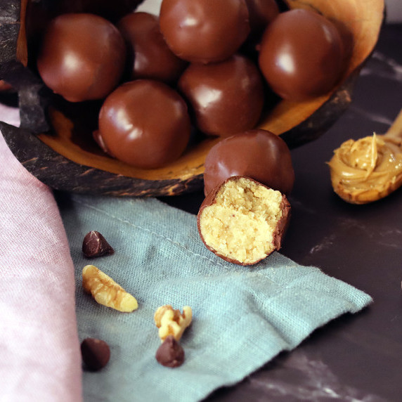 A pile of peanut butter balls with one broken open to show the interior