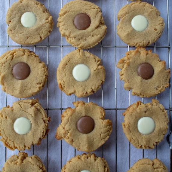 three rows of peanut butter cookies with milk and white chocolate buttons in the center