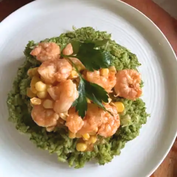 Pesto shrimp served over white rice with vibrant green pesto sauce, garnished with herbs on a plated