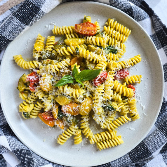 A colourful plate of pasta against a checkered towel.